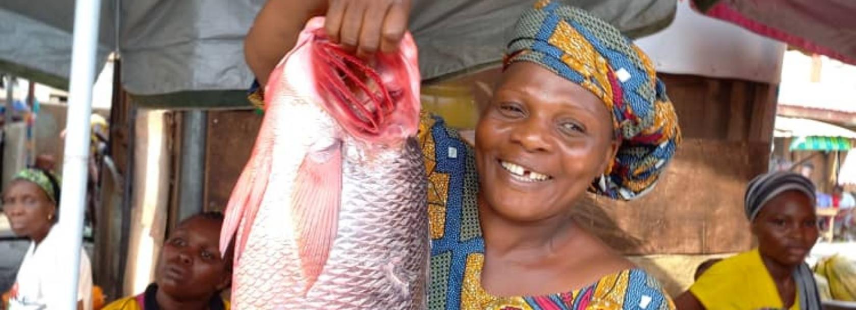 Woman holding fish by a lake, Africa