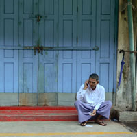 Man on phone sitting in front of blue door